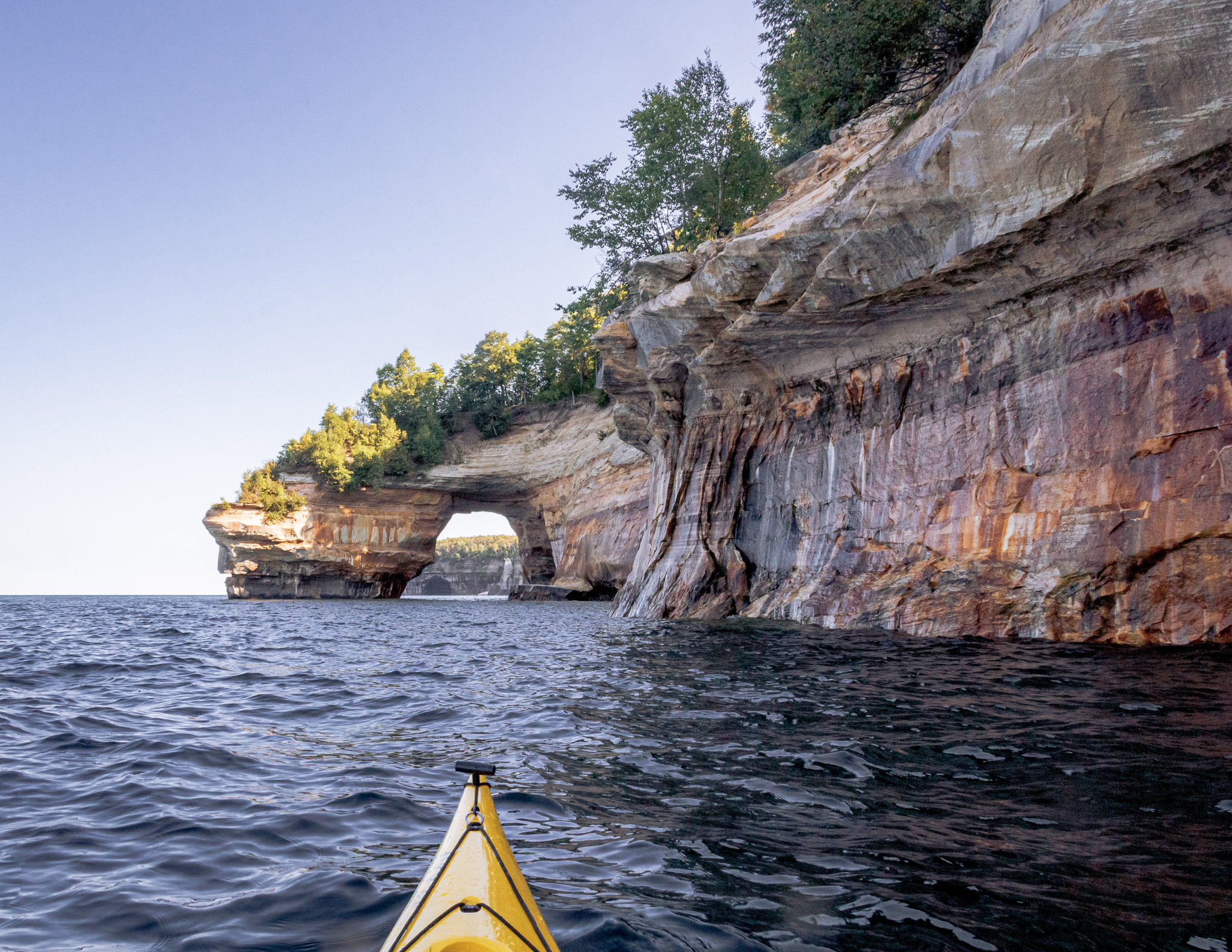 A yellow kayak on Lake Superior under the Pictured Rocks Cliffs
