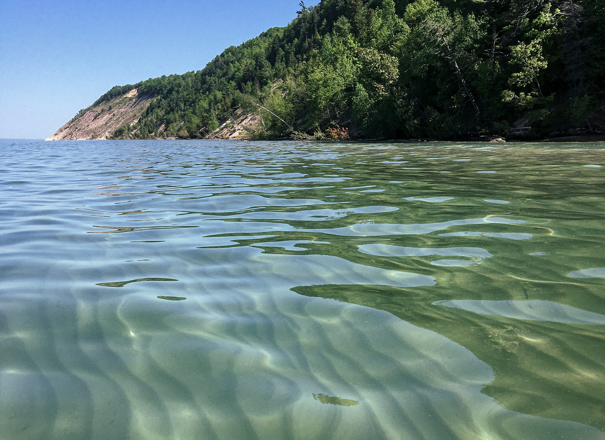 clear water and ripples with Empire Bluff in the background taken from the water at sleeping bear dunes