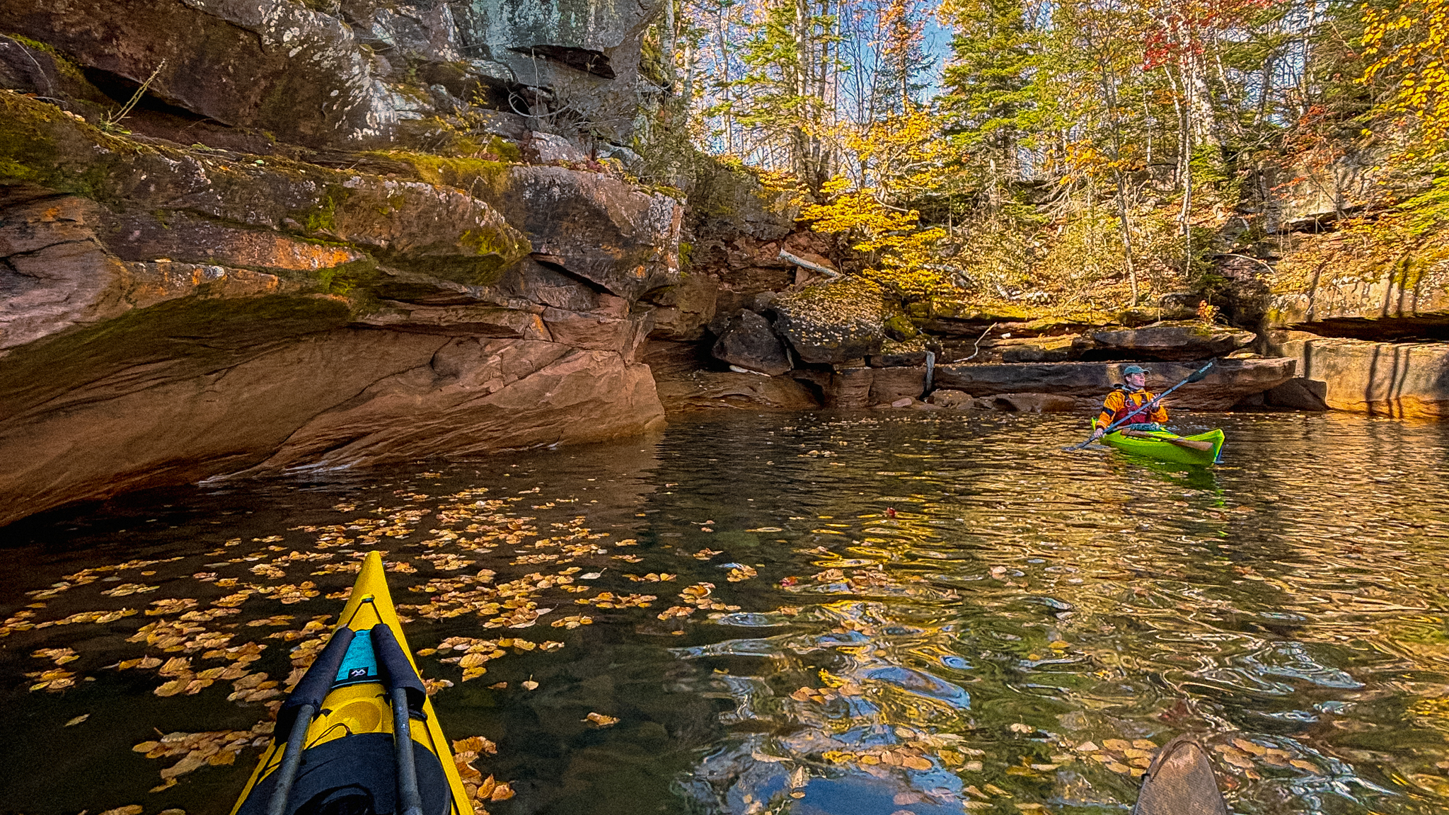 image of kayakers by a cove covered in freshly fallen leaves in wisconsin, peak fall color