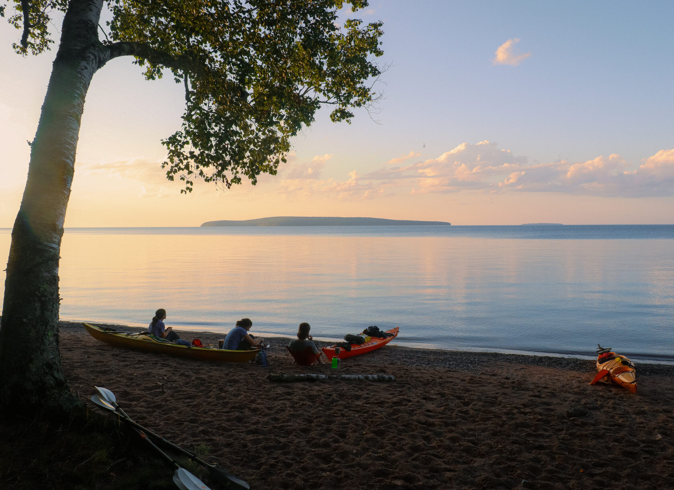 image of three kayakers sitting by the edge of Lake Superior in Northern Wisconsin
