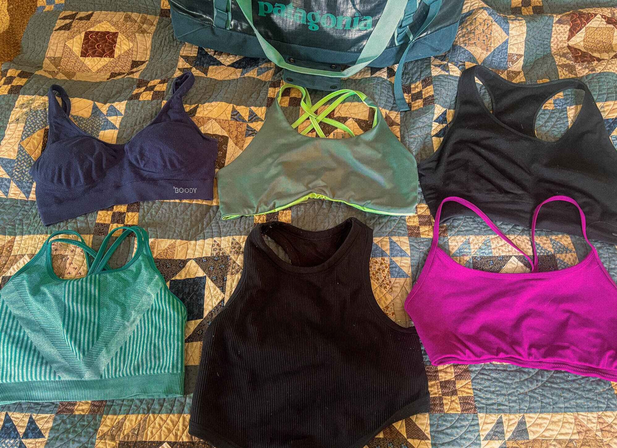 Image of a flat lay of six sports bras spread out on a bed