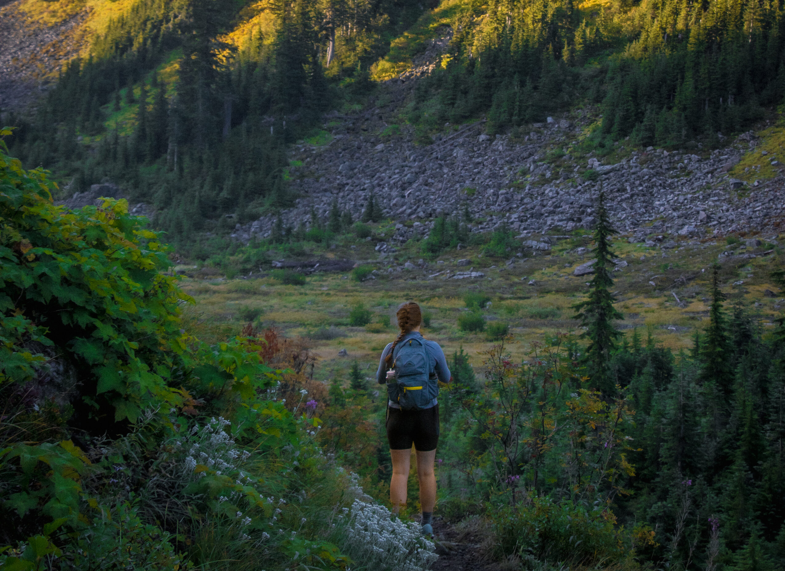 A woman stands in a valley wearing legging style hiking shorts